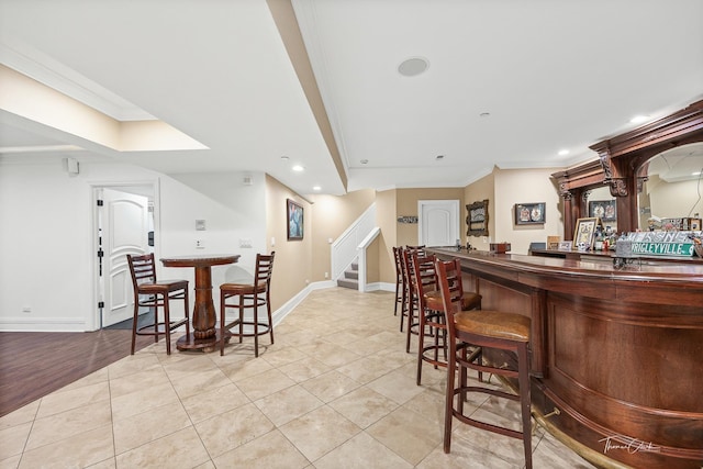 bar with crown molding and light tile patterned flooring