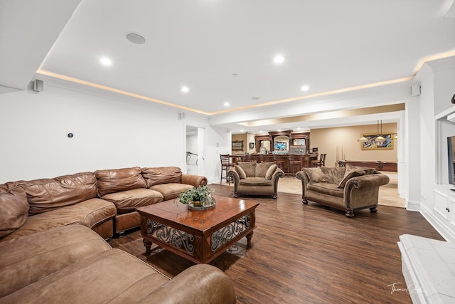 living room featuring dark wood-type flooring, a tray ceiling, and crown molding