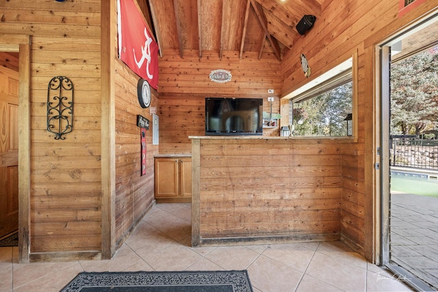 bar with lofted ceiling, light tile patterned floors, and wooden walls