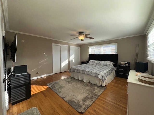 bedroom featuring ceiling fan, multiple windows, and hardwood / wood-style floors