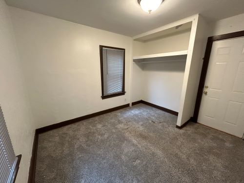 unfurnished bedroom with a closet and dark carpet