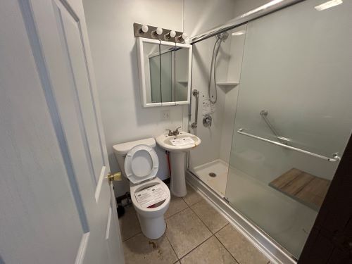 bathroom with a shower with door, toilet, and tile patterned floors