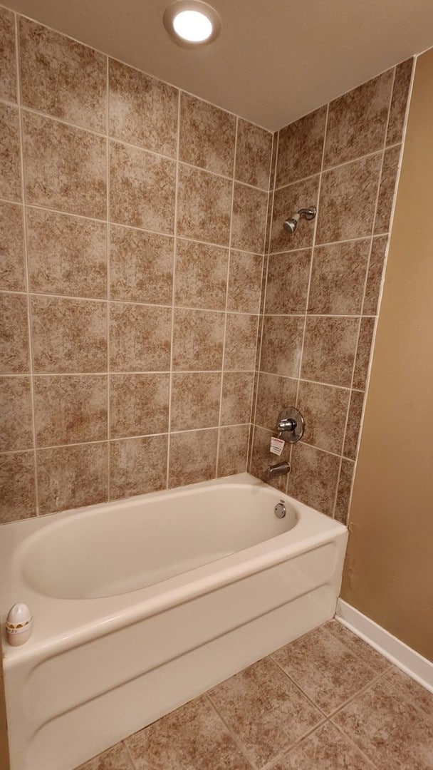 bathroom with tiled shower / bath and tile patterned flooring