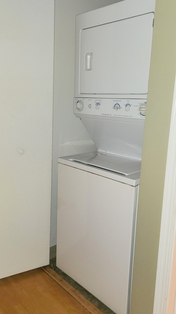 clothes washing area featuring stacked washer / dryer and light wood-type flooring