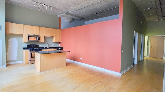 kitchen featuring a center island, stainless steel appliances, a high ceiling, and light wood-type flooring