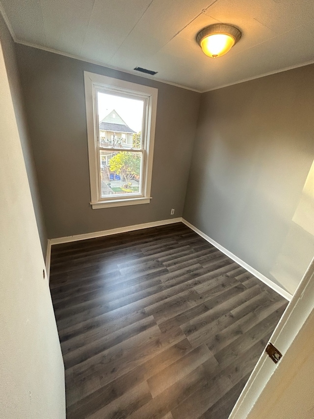 empty room featuring crown molding and dark hardwood / wood-style flooring