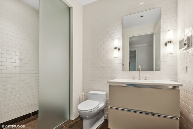 bathroom with tile walls, vanity, hardwood / wood-style flooring, and toilet