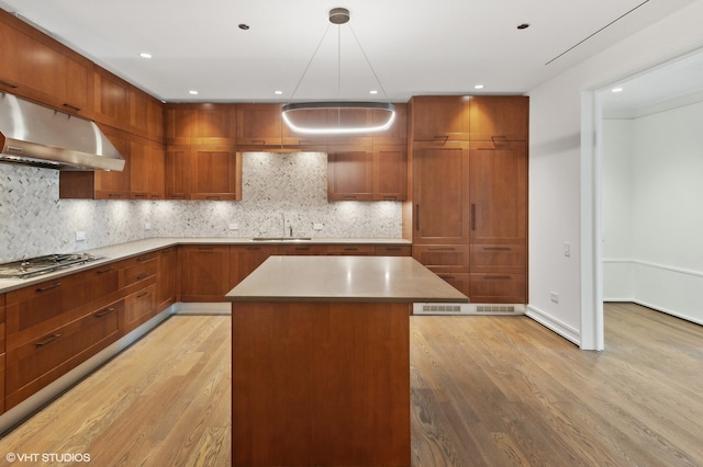 kitchen featuring decorative backsplash, light hardwood / wood-style flooring, stainless steel gas stovetop, and a kitchen island