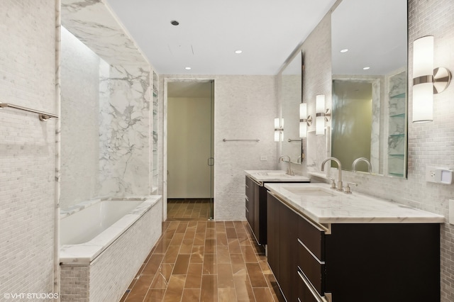 bathroom featuring tiled bath, tile walls, and vanity