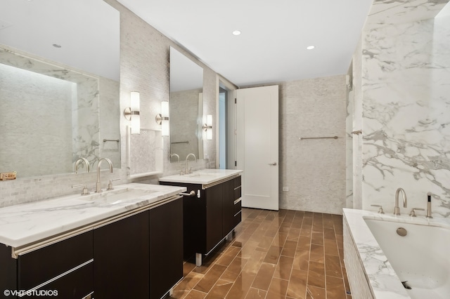 bathroom featuring vanity, tile walls, and tiled bath