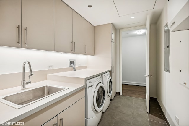 washroom with cabinets, dark tile patterned floors, sink, and washer and dryer