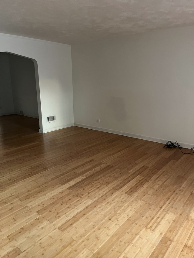 spare room with a textured ceiling and light wood-type flooring