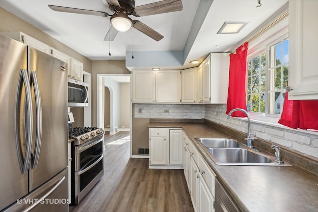 kitchen with white cabinetry, sink, dark wood-type flooring, decorative backsplash, and appliances with stainless steel finishes