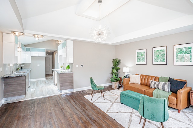 living room with an inviting chandelier, sink, vaulted ceiling, and light wood-type flooring