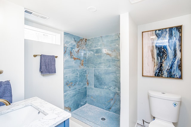 bathroom featuring toilet, vanity, and a tile shower