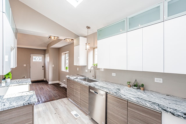 kitchen with dishwasher, wood-type flooring, light stone countertops, lofted ceiling with skylight, and white cabinetry