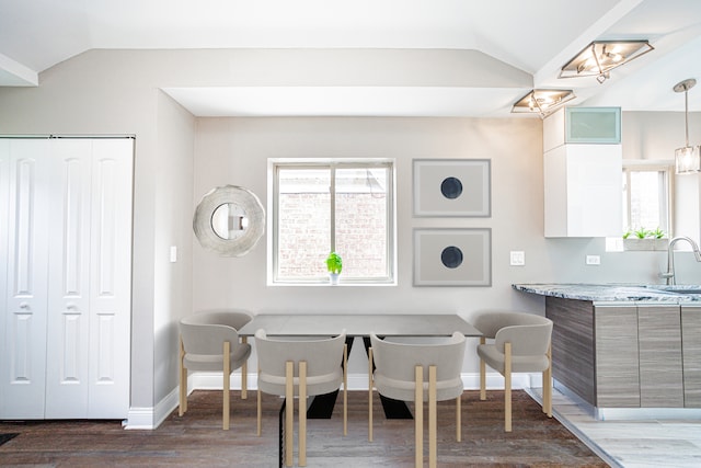 dining room featuring sink, lofted ceiling, and dark hardwood / wood-style flooring