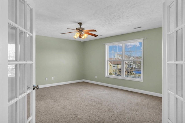 carpeted empty room featuring ceiling fan, french doors, and a textured ceiling