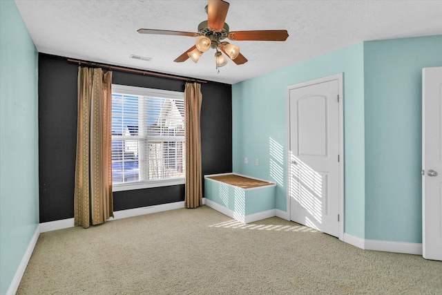 unfurnished room featuring light colored carpet, a textured ceiling, and ceiling fan