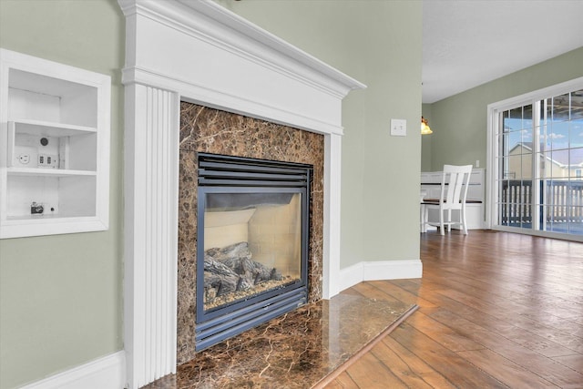 details featuring hardwood / wood-style floors, built in features, and a high end fireplace