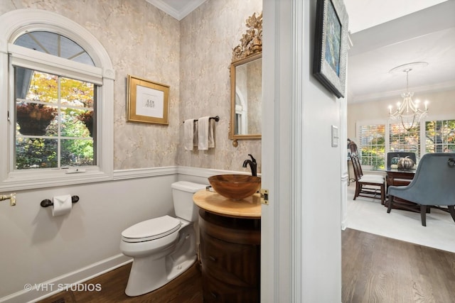 bathroom featuring hardwood / wood-style floors, a chandelier, toilet, vanity, and ornamental molding