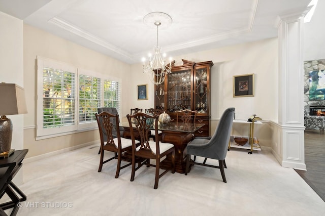 dining room featuring a raised ceiling, ornate columns, and light colored carpet