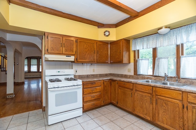 kitchen featuring sink, white gas range, light hardwood / wood-style floors, beamed ceiling, and decorative backsplash