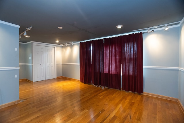 spare room featuring rail lighting, wood-type flooring, and ornamental molding