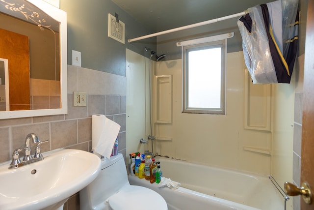 full bathroom with toilet, backsplash, sink, tile walls, and washtub / shower combination