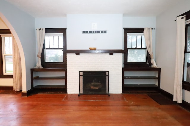 unfurnished living room with plenty of natural light, dark hardwood / wood-style flooring, and a brick fireplace