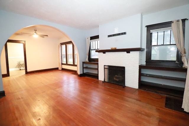 unfurnished living room featuring a brick fireplace, ceiling fan, and hardwood / wood-style flooring