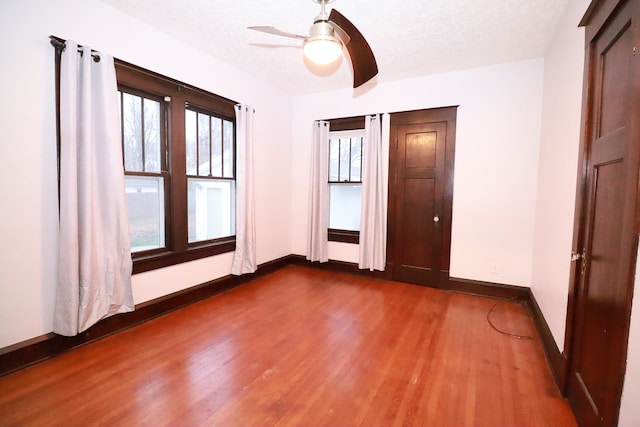 unfurnished bedroom featuring a textured ceiling, ceiling fan, and dark wood-type flooring