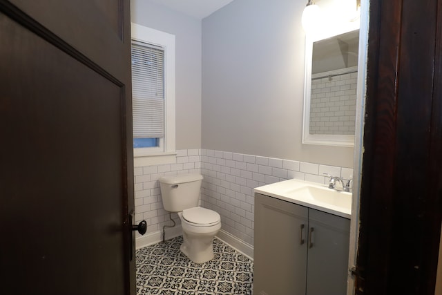 bathroom with tile patterned floors, vanity, toilet, and tile walls