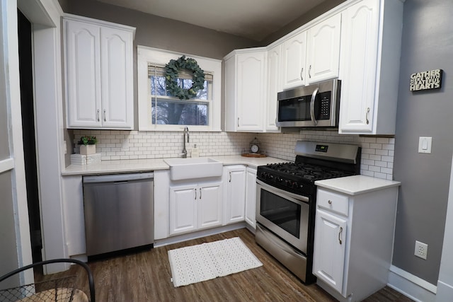 kitchen with dark hardwood / wood-style flooring, backsplash, stainless steel appliances, sink, and white cabinets