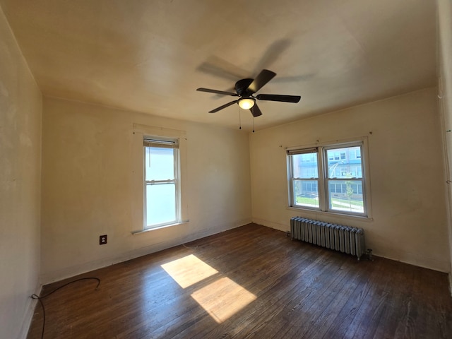 spare room with radiator heating unit, ceiling fan, and dark hardwood / wood-style flooring