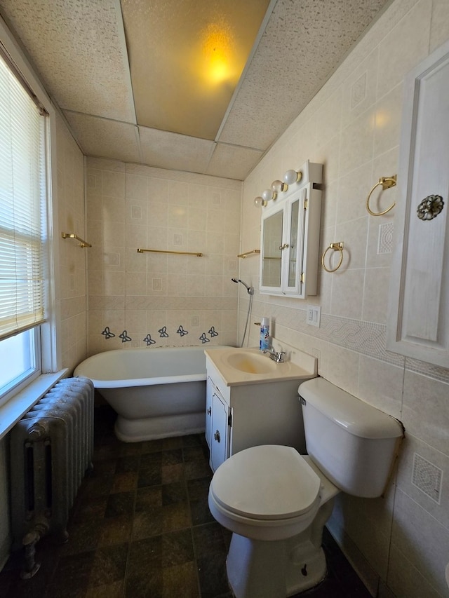 bathroom featuring toilet, a bathing tub, tile walls, vanity, and radiator heating unit