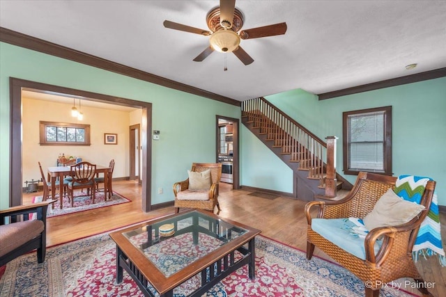 living room featuring crown molding, ceiling fan, and light hardwood / wood-style floors