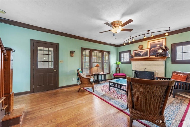 living room featuring crown molding, a textured ceiling, a fireplace, and light hardwood / wood-style flooring