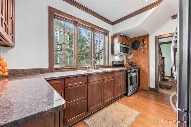 kitchen with ornamental molding, appliances with stainless steel finishes, sink, and light hardwood / wood-style flooring