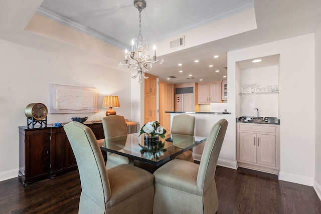 dining room featuring dark hardwood / wood-style flooring, sink, a tray ceiling, and ornamental molding