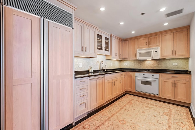 kitchen with white appliances, light brown cabinetry, and sink