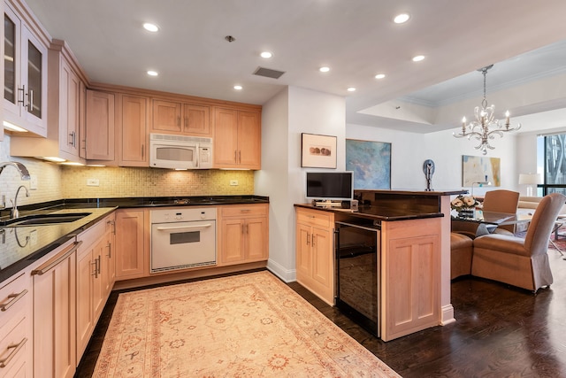 kitchen featuring pendant lighting, sink, white appliances, dark hardwood / wood-style floors, and a tray ceiling