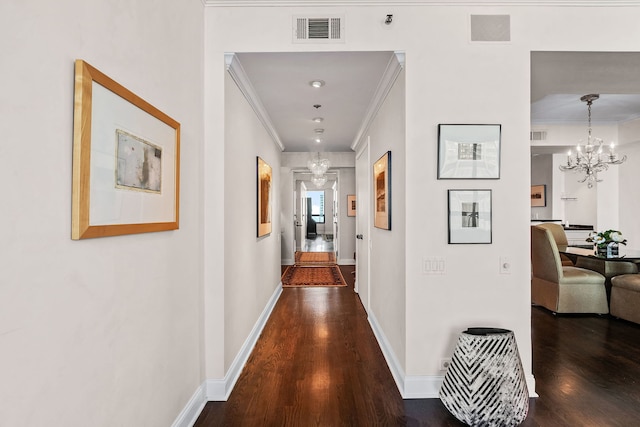 corridor with hardwood / wood-style flooring, ornamental molding, and a chandelier