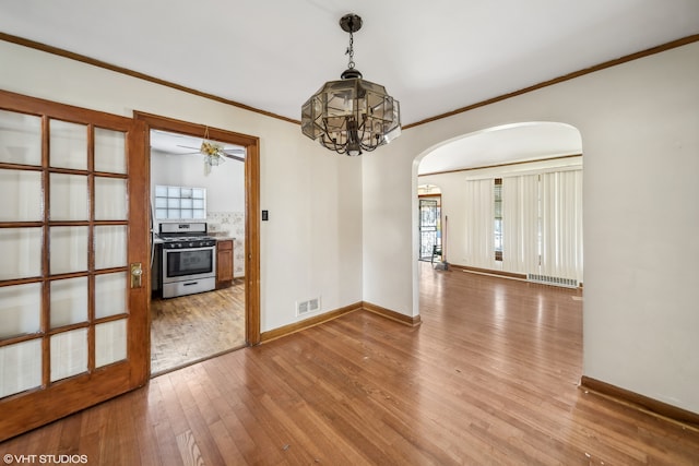 spare room featuring hardwood / wood-style floors, ceiling fan with notable chandelier, and crown molding