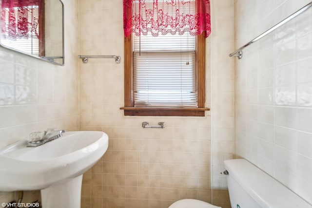 bathroom featuring tile walls and toilet