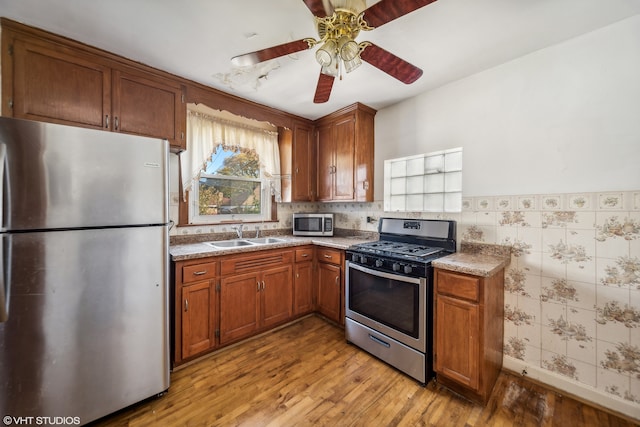 kitchen featuring appliances with stainless steel finishes, sink, ceiling fan, and light hardwood / wood-style flooring