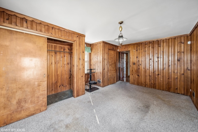 unfurnished bedroom with light colored carpet and wood walls