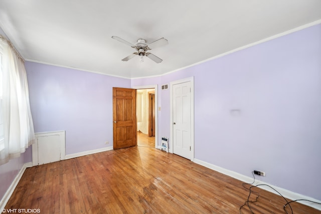 spare room featuring light wood-type flooring, ceiling fan, and crown molding