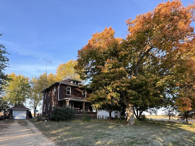 view of property exterior featuring a garage, a yard, an outdoor structure, and covered porch