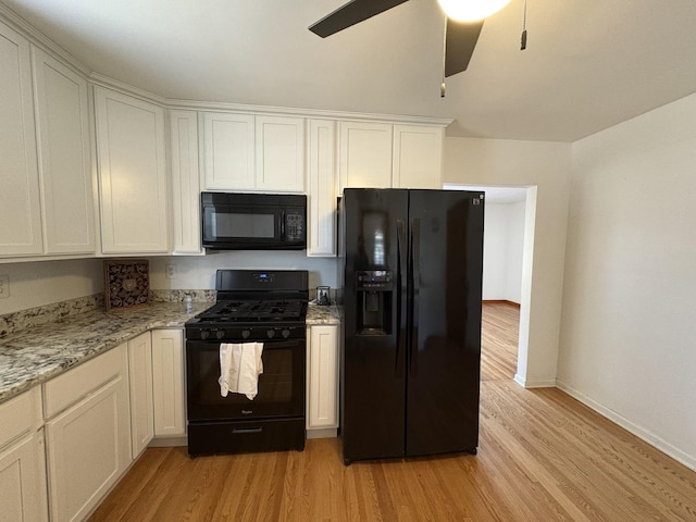 kitchen with light stone countertops, black appliances, white cabinets, and light wood-type flooring